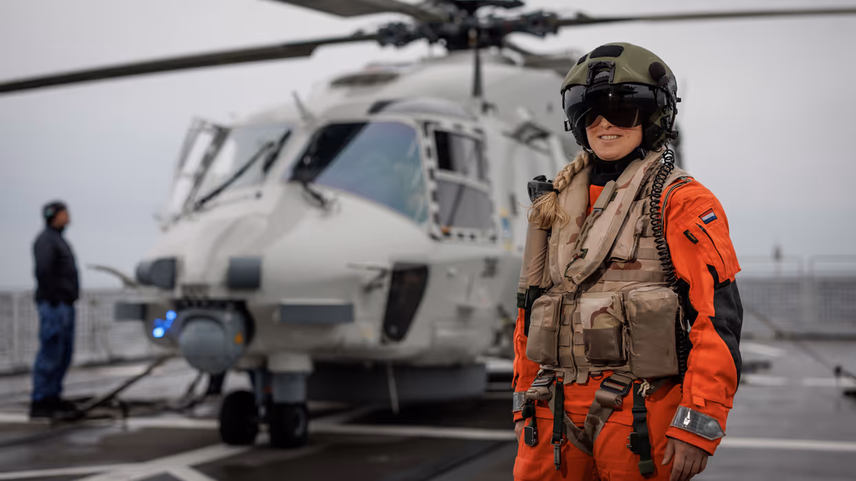 Een piloot met haar helikopter achter haar.