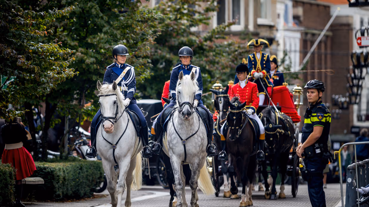 Militairen te paard in een colonne.