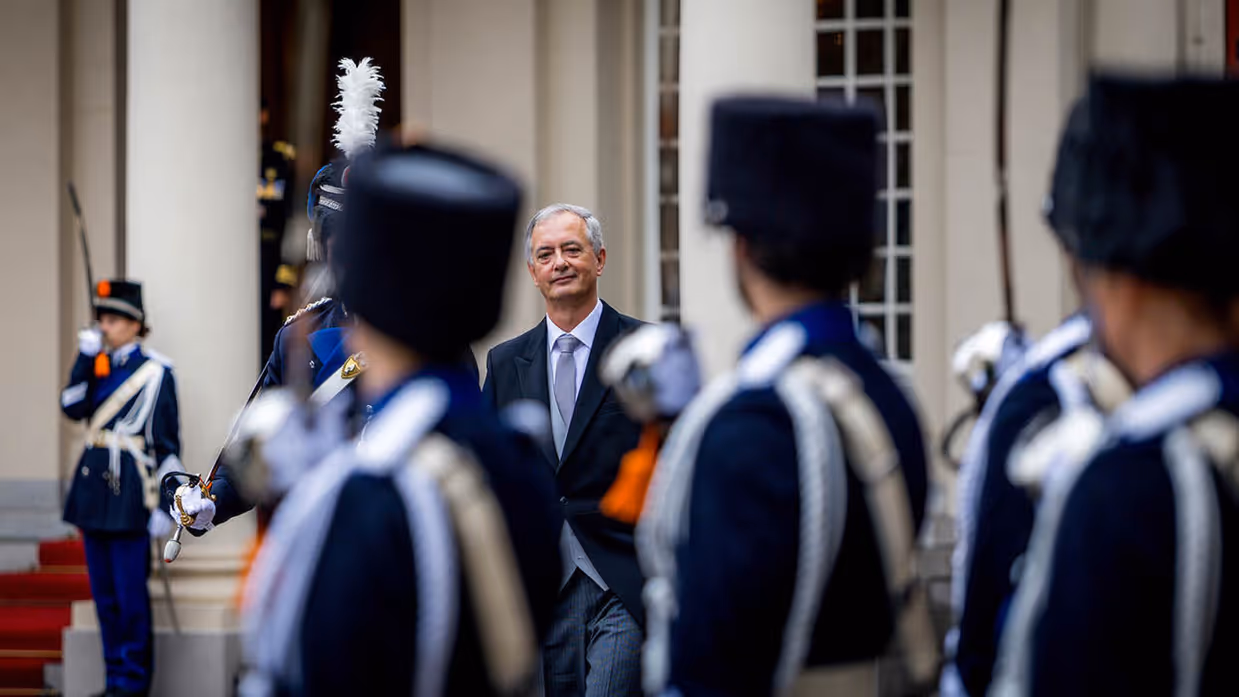 Een ambassadeur kijkt toe op militairen in ceremonieel ornaat.