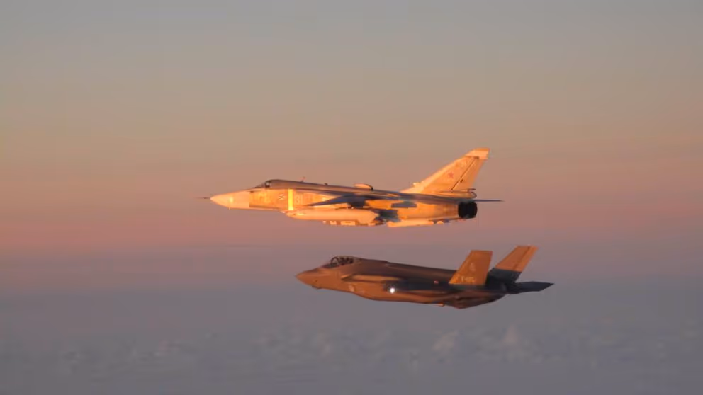 F-35 begeleidt een Russisch vliegtuig in de lucht.