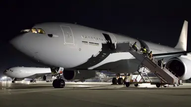  Twee A330 MRTT’s staan in het donker op een platform en worden verlicht door lampen.