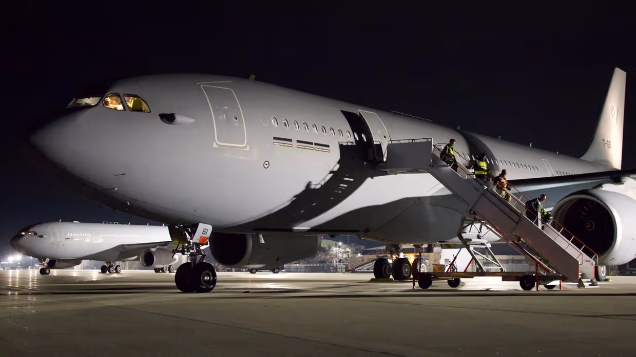  Twee A330 MRTT’s staan in het donker op een platform en worden verlicht door lampen.