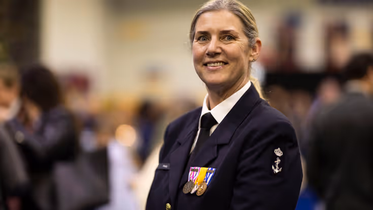 Militair in uniform kijkt lachend in camera. 