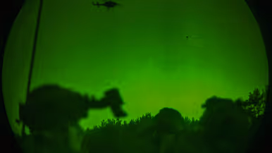 Foto’s van de Live Fire-oefening door een nachtkijker genomen waarbij vanuit een helikopter wordt geschoten.