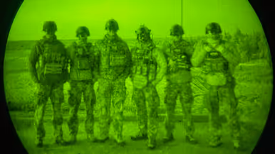 Foto’s van de Live Fire-oefening door een nachtkijker genomen waarbij vanuit een helikopter wordt geschoten.