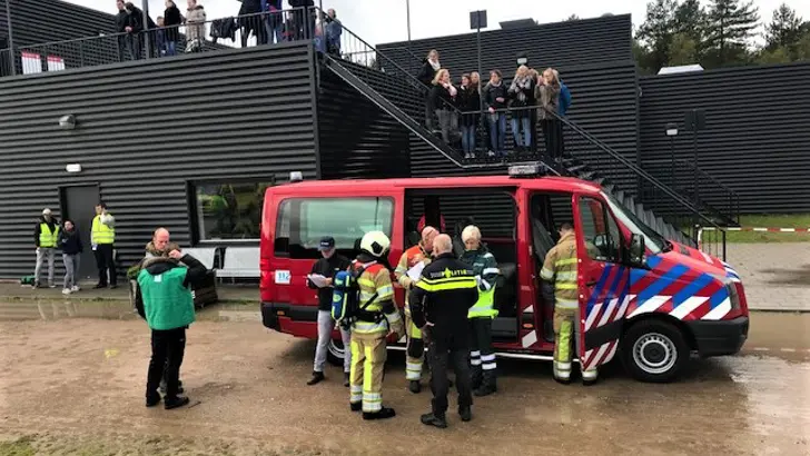 Mensen wachten buiten op metrostation. Brandweerwagen en hulpverleners aanwezig.