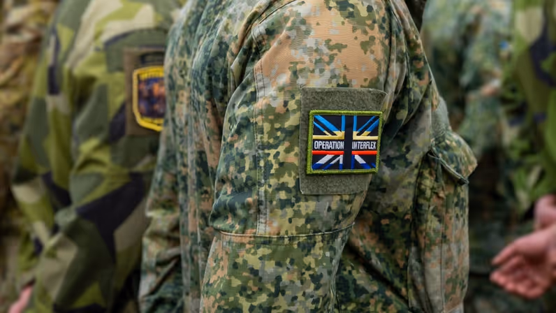 Op schouder van militair een patch met de tekst ‘Operation Interflex’.