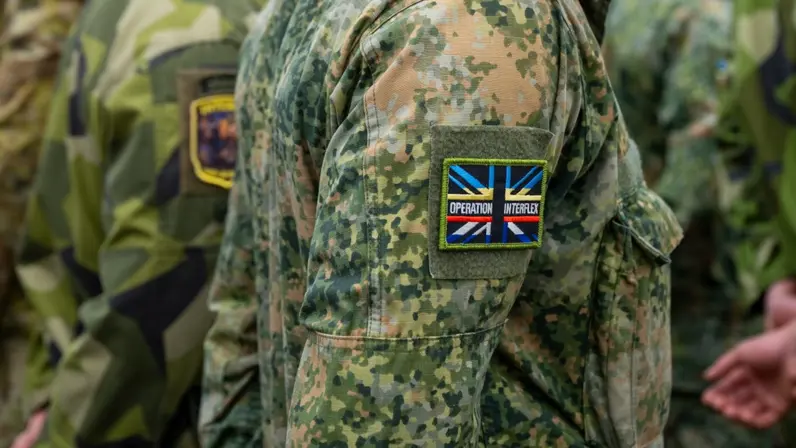 Op schouder van militair een patch met de tekst ‘Operation Interflex’.