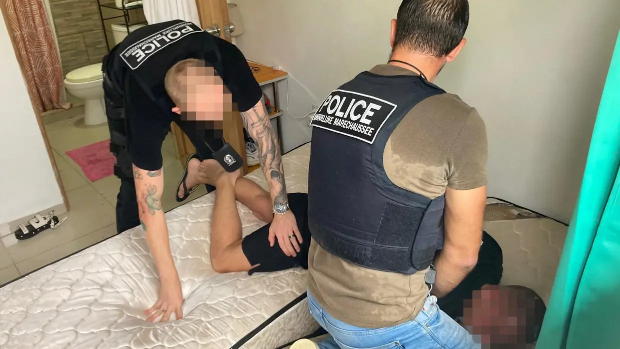 Marechaussees van de DGC boeien een man op een matras.