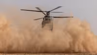 Chinook-transporthelikopter maakt stofwolk vlak boven de grond.