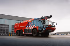 Brandweervoertuig met veel rood, blauwwitte strepen en grote glazen cabine.