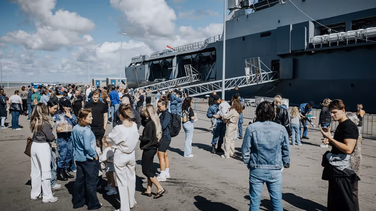Familie en vrienden zwaaien de bemanning uit op de kade.
