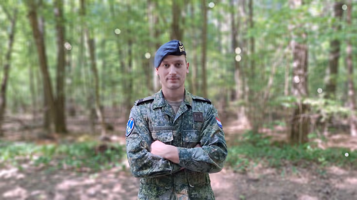 Sergeant Jorrin staat met armen over elkaar met een bos op de achtergrond. Foto: Defensie