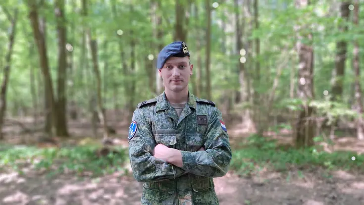 Sergeant Jorrin staat met armen over elkaar met een bos op de achtergrond. Foto: Defensie