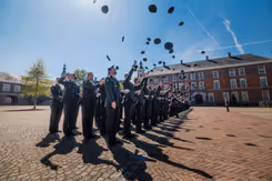 Cadetten van de KMA gooien hun hoofddeksels in de lucht.
