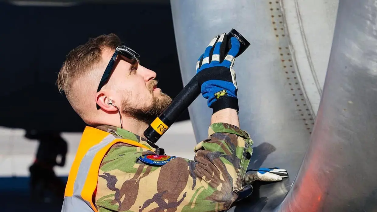 Technici staan onder de geopende motorgondel van een KDC-10 in een onderhoudshangar.