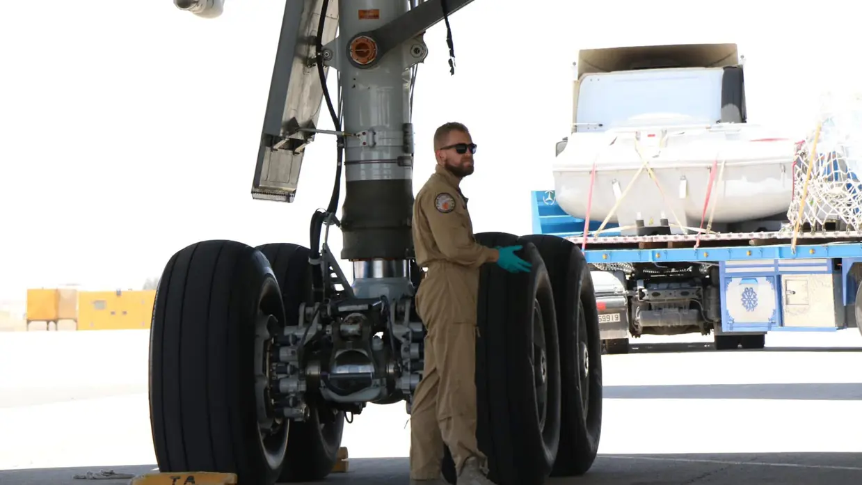 Technici staan onder de geopende motorgondel van een KDC-10 in een onderhoudshangar.