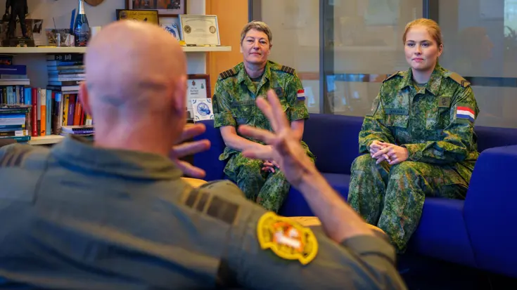 De prinses zit in een kamer met commandant Koninklijke Luchtmacht luitenant-generaal André Steur en commandant Groep Luchtmacht Reserve kolonel Martine Verhulst.