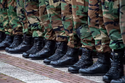 Close-up van voeten en onderbenen gestoken in legerkisten en camouflage kleding.