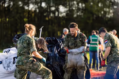 Mannelijke  en vrouwelijke militairen zijn bezig met zandzakken.