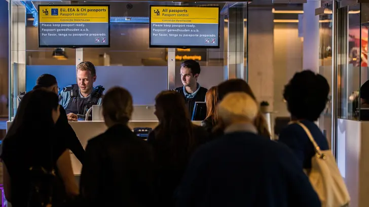 2 marechaussees bij de paspoortcontrole controleren reisdocumenten.