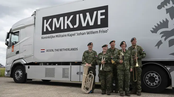 De 5 leden van het Koperkwintet staan voor een vrachtwagen met de tekst: KMKJWF Koninklijke Militaire Kapel 'Johan Willem Friso' Assen, The Netherlands.