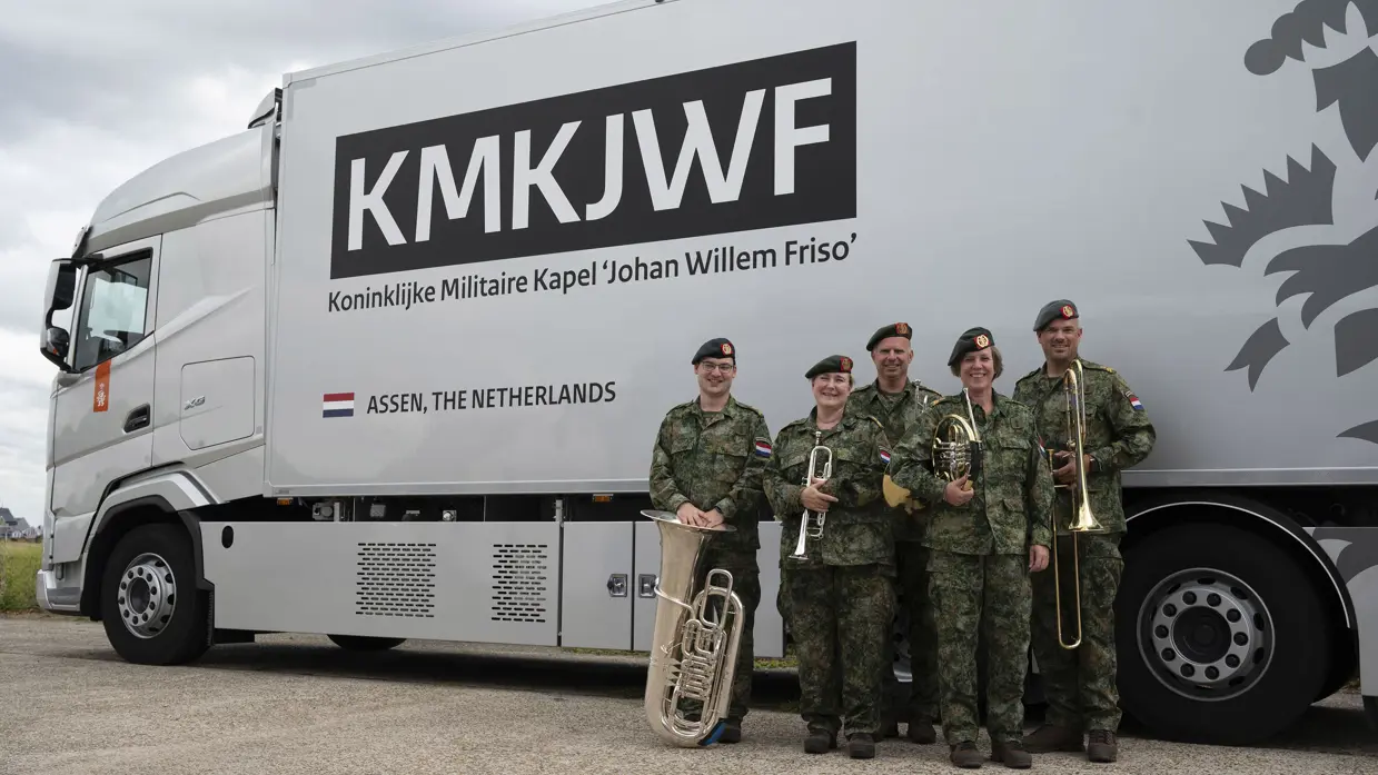 De 5 leden van het Koperkwintet staan voor een vrachtwagen met de tekst: KMKJWF Koninklijke Militaire Kapel 'Johan Willem Friso' Assen, The Netherlands.