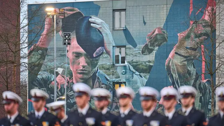 Militairen op een rij voor grote muurschildering.