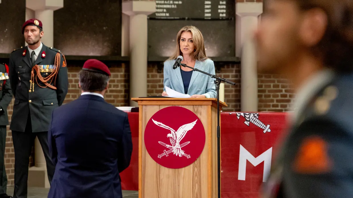 Wintersberger gezien van op de rug, terwijl de minister hem toespreekt.