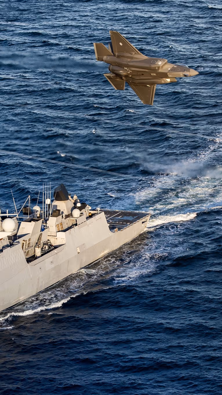 Een LCF op zee, 2 F-35’s vliegen over.