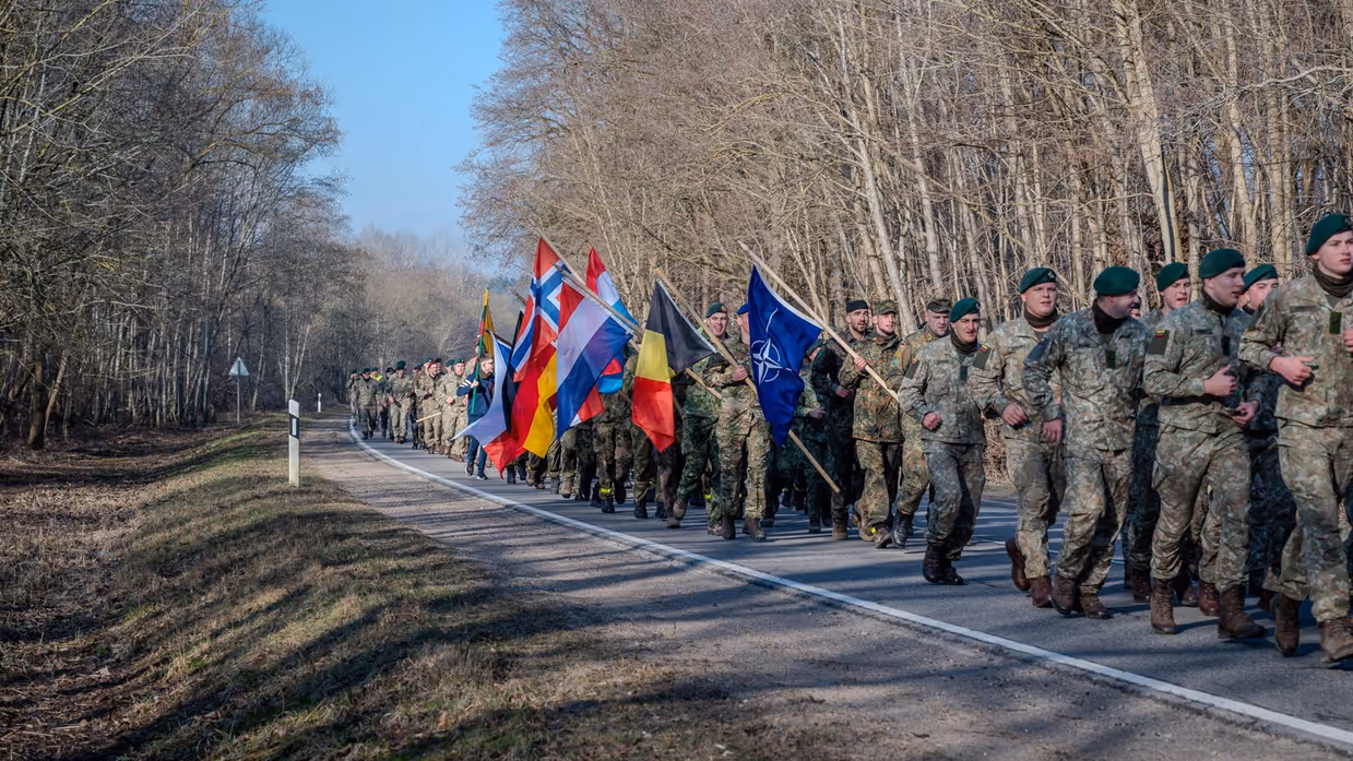 Militairen marcheren met vlaggen in de hand.