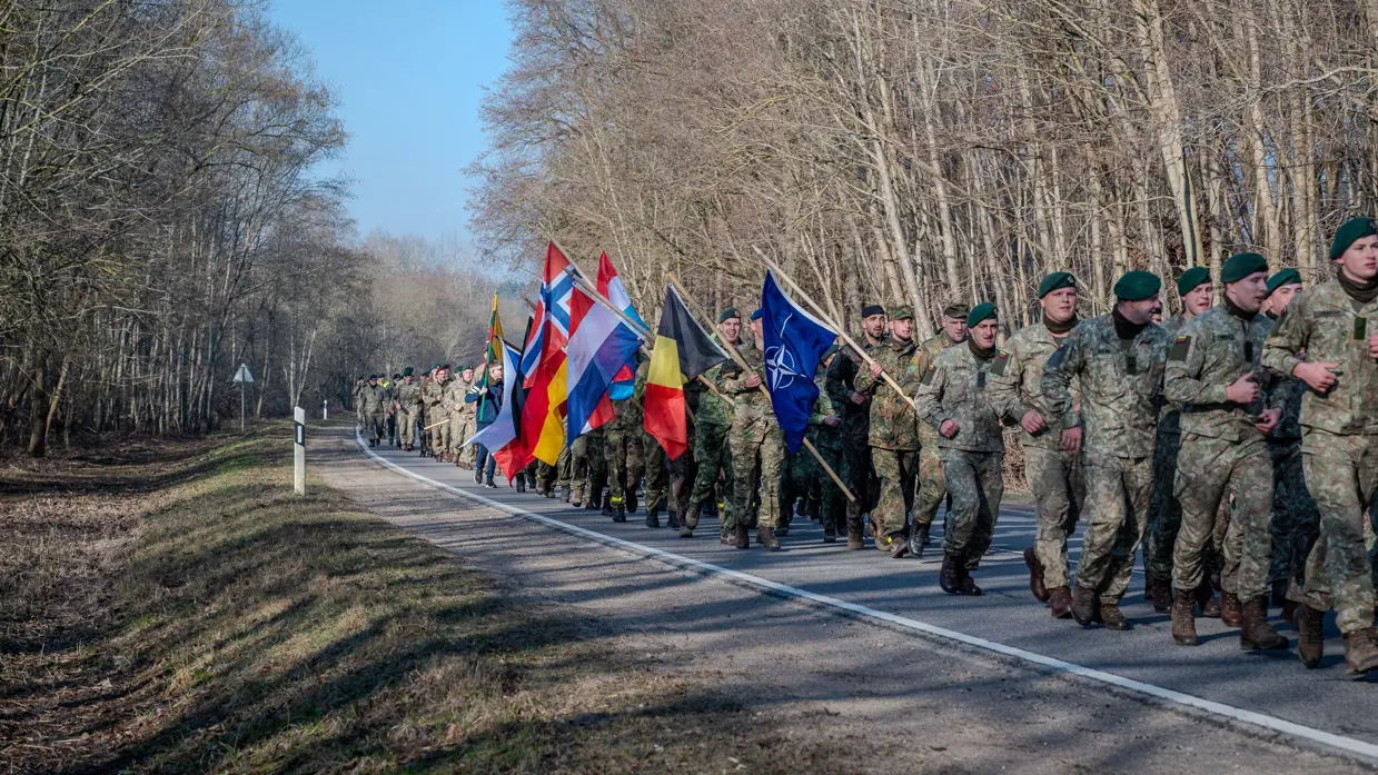Militairen marcheren met vlaggen in de hand.