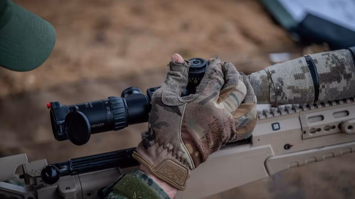 Hand militair die vizier geweer afstelt.