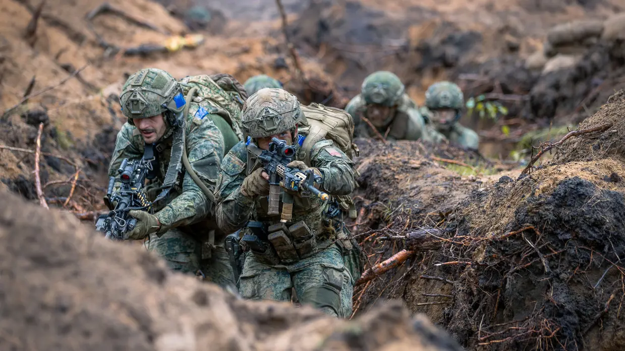 Militairen kruipen door loopgraven.