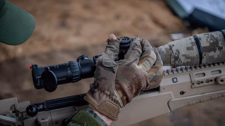 Hand militair die vizier geweer afstelt.