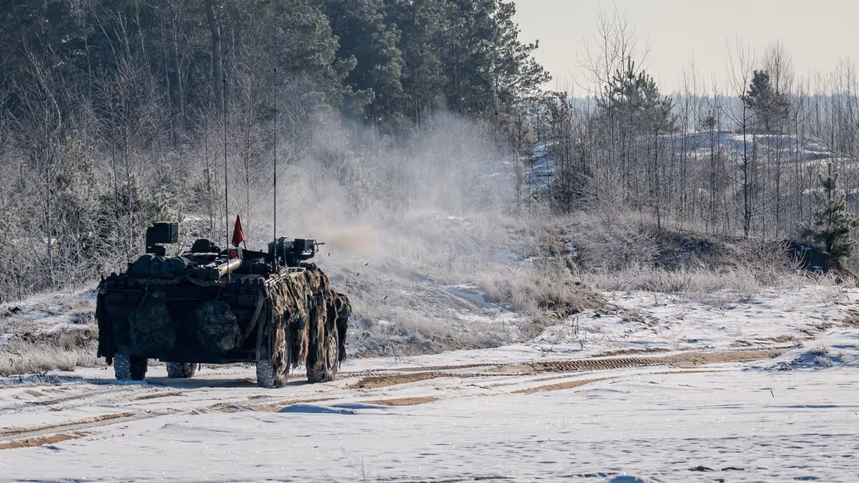 Militair voertuig rijdt door een besneeuwd landschap.