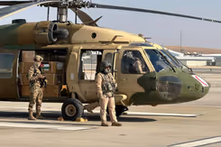 Helikopter staat aan de grond met 2 militairen erbij.