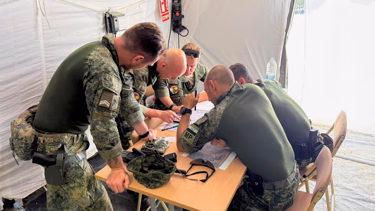 Militairen gebogen over een kaart tijdens oefening Angel Guardian.