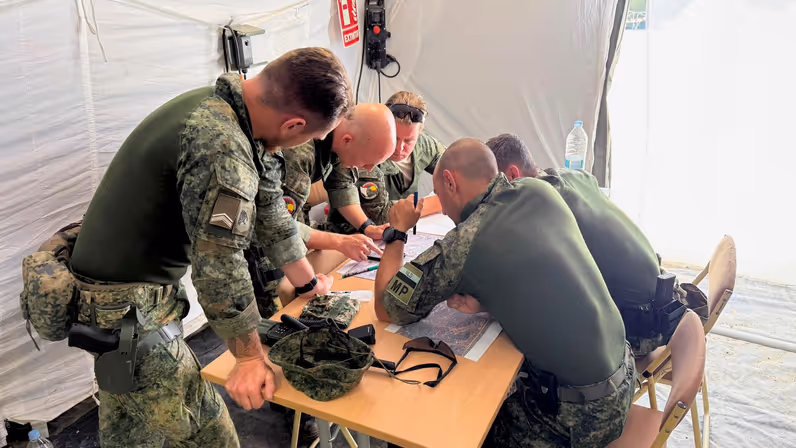 Militairen gebogen over een kaart tijdens oefening Angel Guardian.