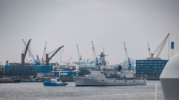 Een marineschip vaart de haven binnen.