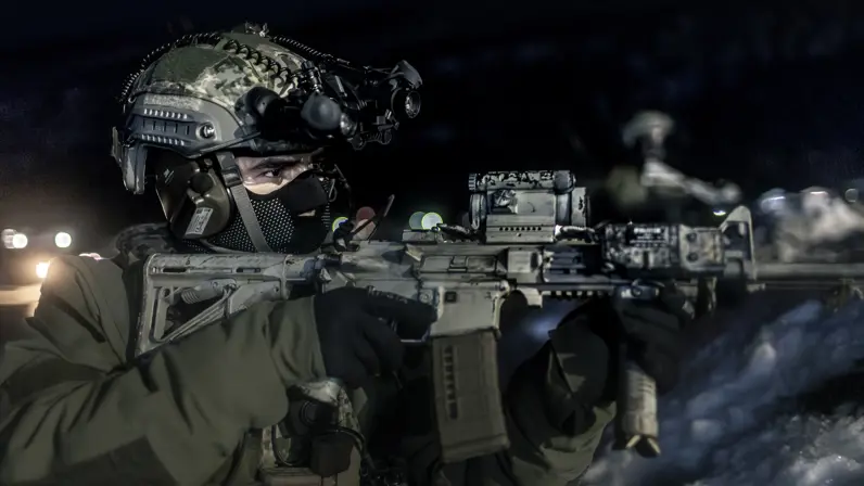 Marinier met helm en gezichtsmasker richt zijn wapen.