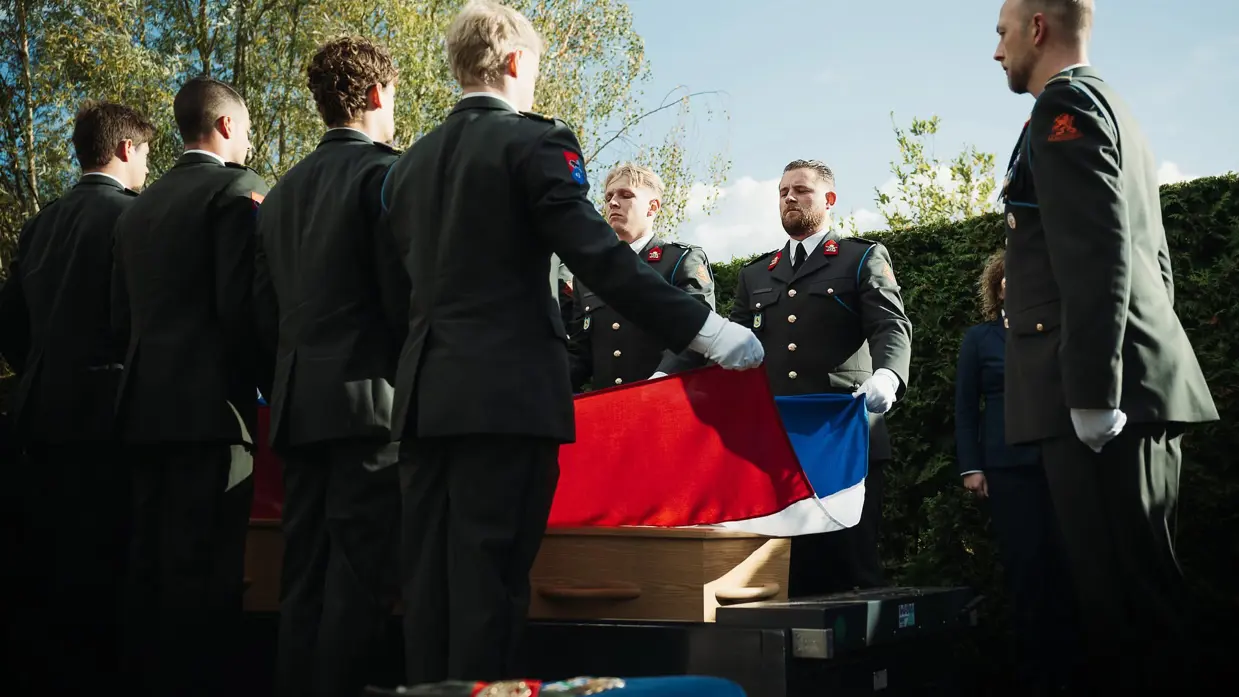  Mix van beelden van Mark. Zo zien we dat zijn kist wordt gedragen door militairen en dat zijn baret en onderscheidingen plechtig worden gedragen door een collega.