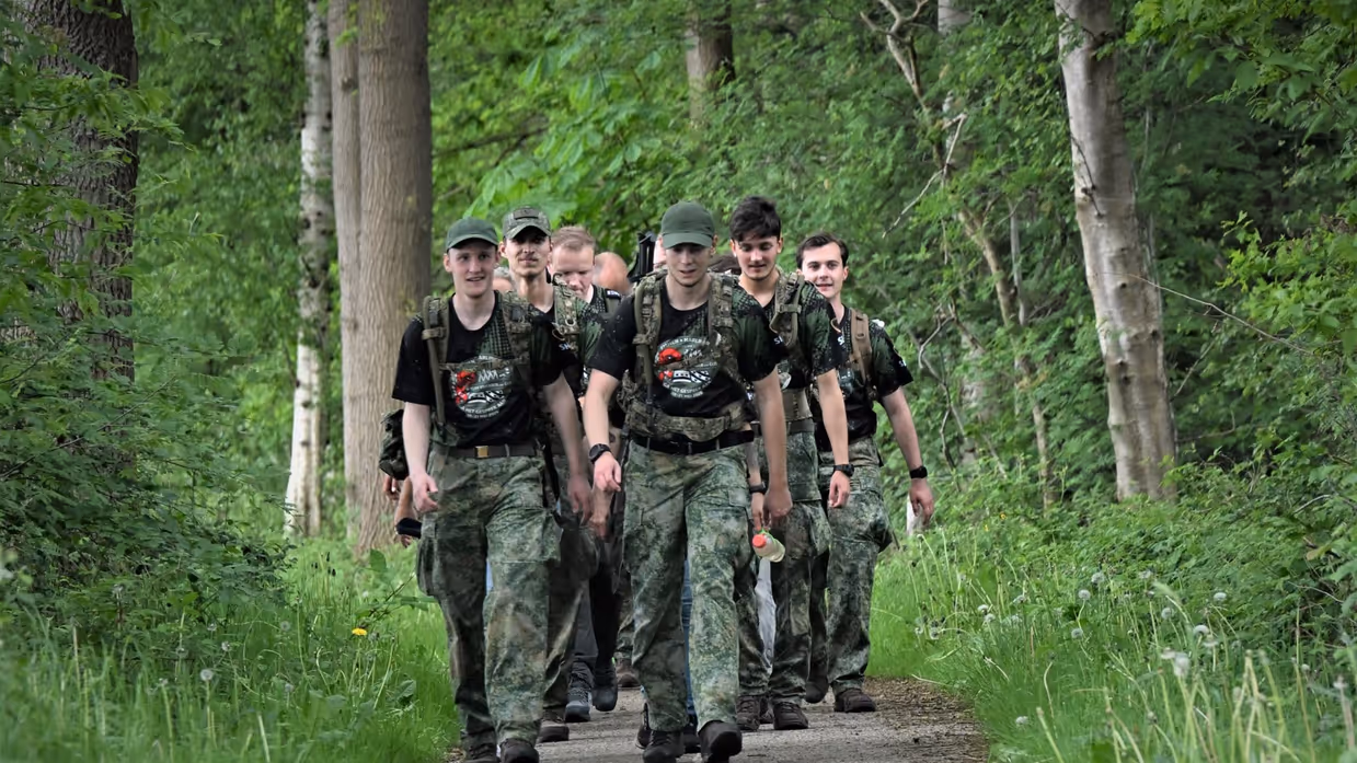 Militairen lopen over een pad door het bos. 
