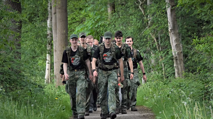 Militairen lopen over een pad door het bos. 