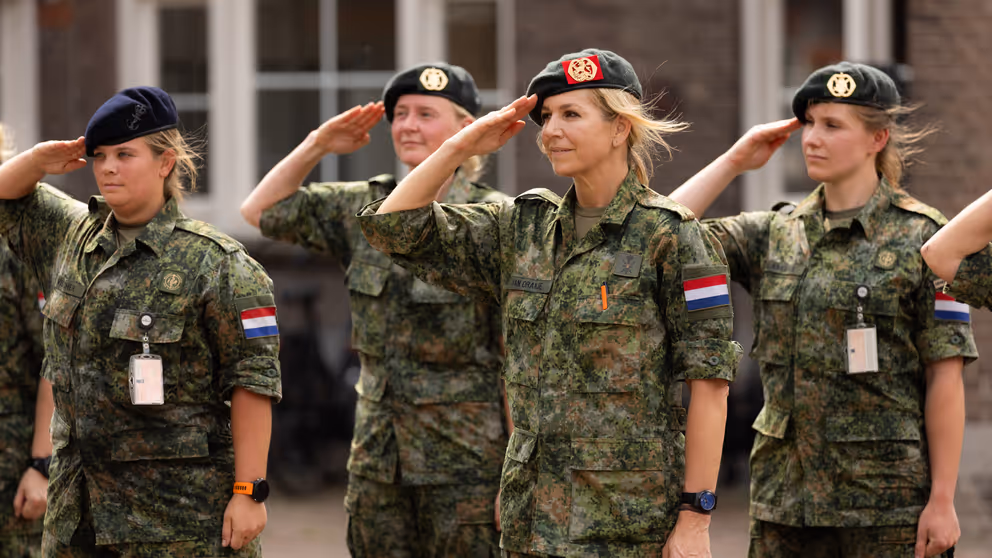 Militairen salueren, onder hen de koningin.