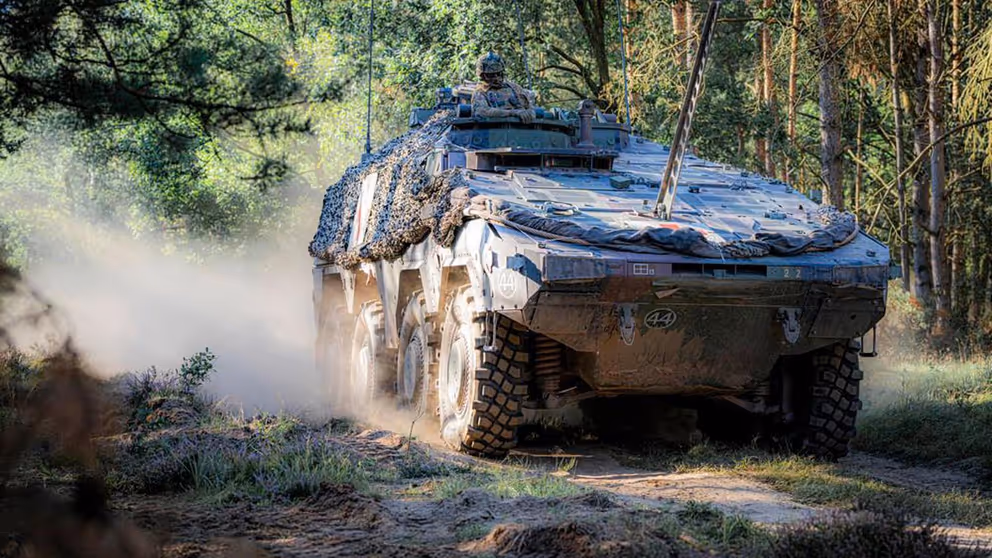 Militair voertuig in bosrijke omgeving.