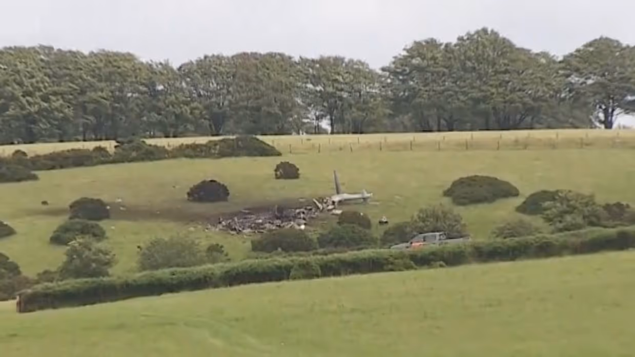 Een neergestorte helikopter ligt in een weiland.