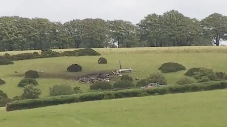 Een neergestorte helikopter ligt in een weiland.