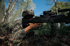 Een militair ligt op de grond met een vuurwapen. 