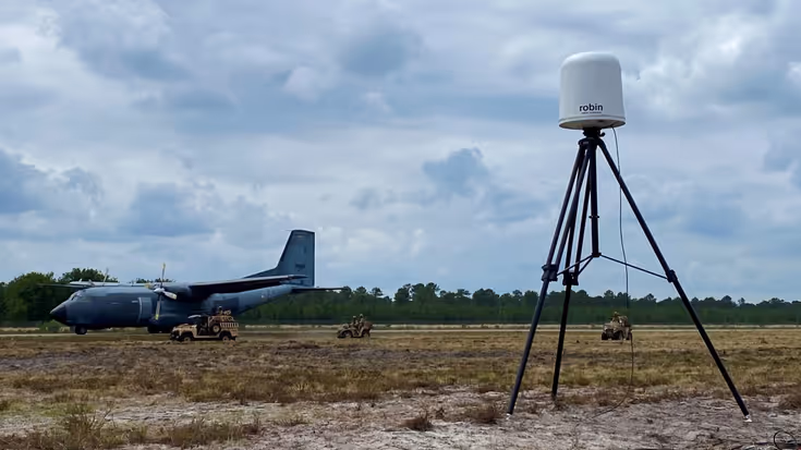  Een radarsysteem in een veld, daarachter een militair vliegtuig.